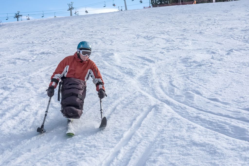 Skieur en fauteuil sur une piste enneigée